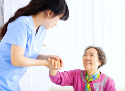 caregiver assisting senior woman to stand up